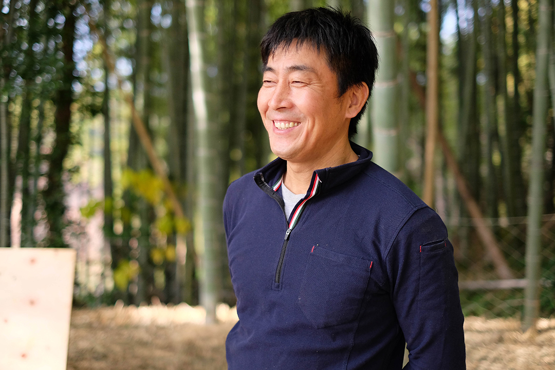 竹林の中で微笑む山本たけのこ代表の山本由人さんの画像