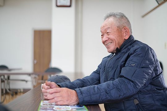 漁協の一室でインタビューに答える笑顔の岡田新治さんの画像