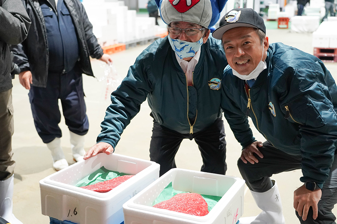 イワシクジラの赤身が入った箱を前にして笑顔の所社長と前田市長の画像