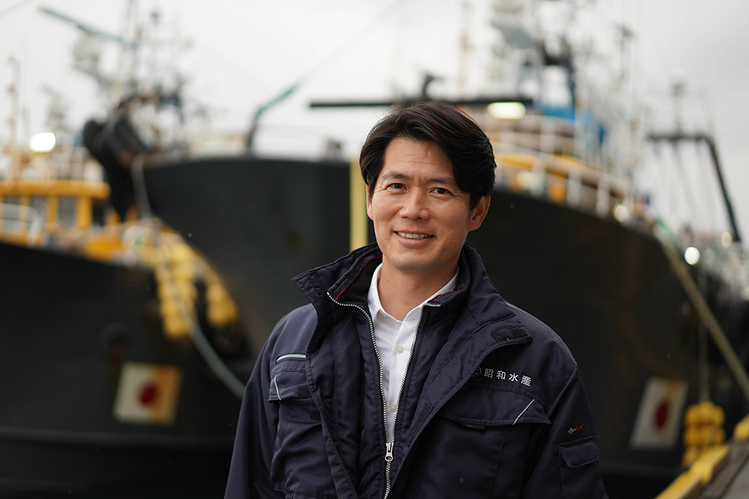 ２隻の船の前で微笑む宮本洋平さんの画像