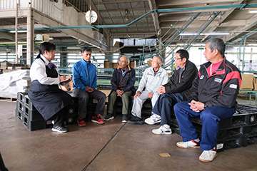 選果場内に座って談笑する柳井さつきさんと豊田梨共同出荷組合の皆さんの画像