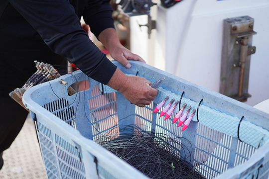 松村秀昭さんが漁に使う仕掛けの入ったカゴを見せてくれている画像
