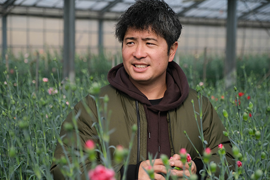 カーネーションのハウスの中にいる植村恵介さんの画像