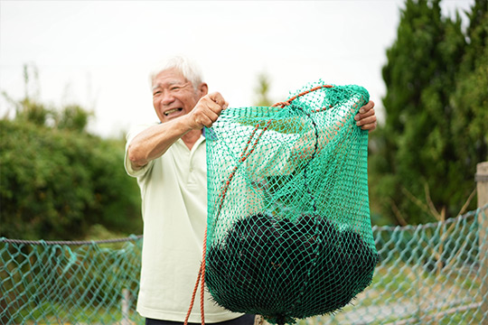 ムラサキウニの網を持ち上げる中村求さん