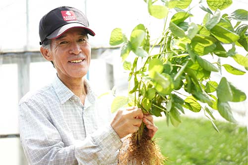 収穫したエダマメを持つ西川吉彦さん